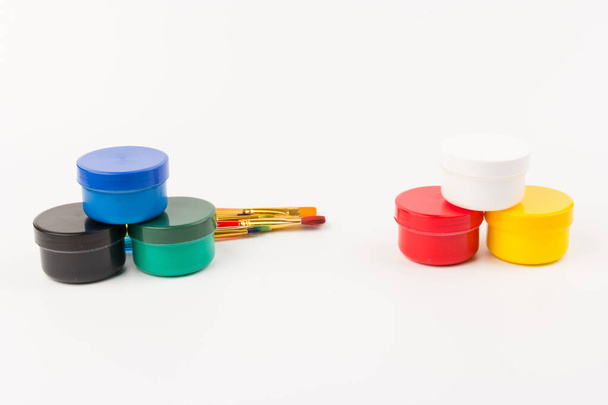 Geschlossene Plastikdosen mit Farbe in verschiedenen Farben für die Kreativität der Kinder auf weißem Hintergrund. Materialien für Zeichnung, Kreativität, frühkindliche Entwicklung. - Foto, Bild