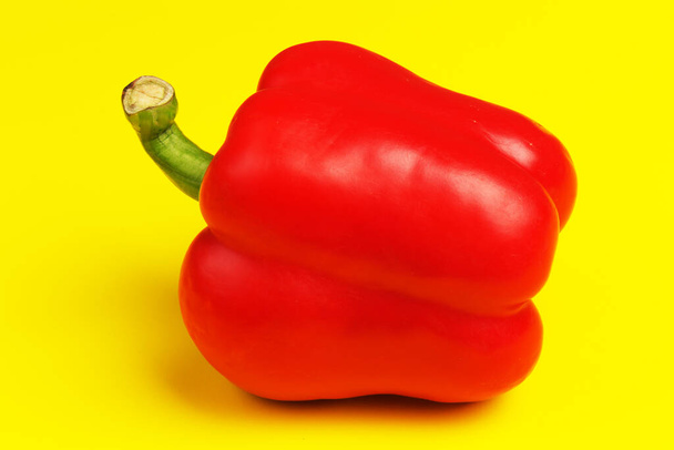 Šťavnaté, světlé a krásné jeden červený paprika na žlutém pozadí zblízka - Fotografie, Obrázek
