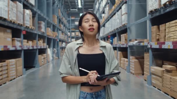 Unhappy young Asia businesswoman looking and feeling confused using digital tablet checking inventory levels standing in retail shopping center. Distribution, Logistics, Packages ready for shipment. - Footage, Video