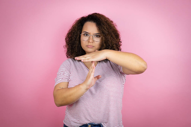 Młoda Afroamerykanka w czerwonych paskach koszulka na różowym tle Wykonuje gest rękami, sfrustrowana i poważna twarz - Zdjęcie, obraz