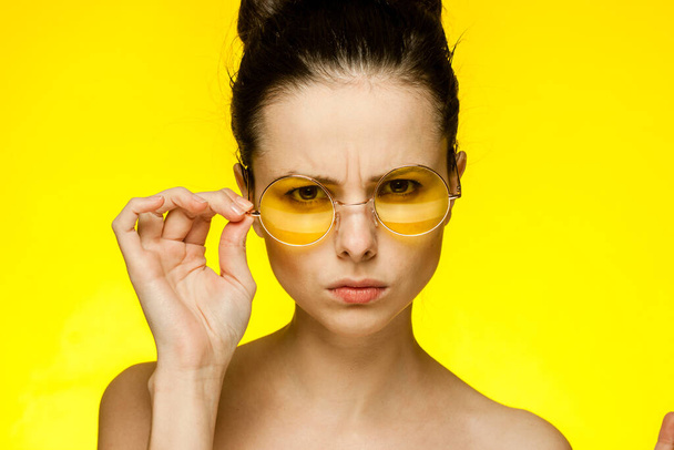 bonita mujer divertido amarillo gafas desnudo hombros aislado fondo - Foto, Imagen
