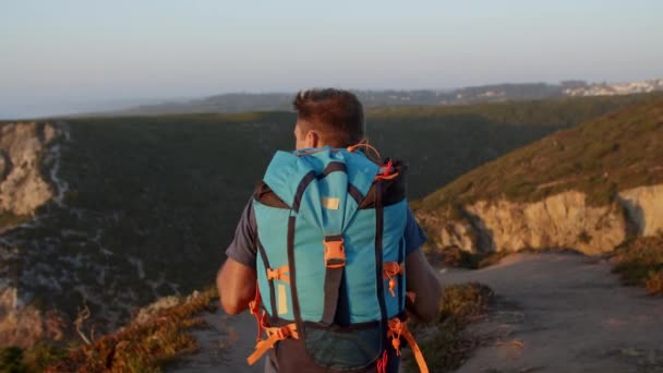 Aktiivinen reppumatkailija kävelee polkua pitkin vuorilla - Materiaali, video