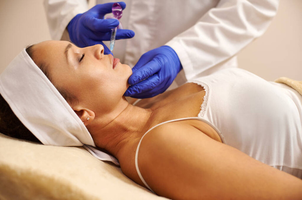 Vista lateral de una hermosa mujer recibiendo tratamiento de lifting facial en el salón de spa. Concepto de cosmetología por inyección - Foto, imagen