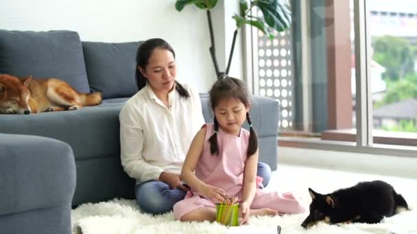Eine alleinerziehende Mutter mit ihrer Tochter in einem Wohnzimmer mit einem braunen Shiba Inu. - Filmmaterial, Video