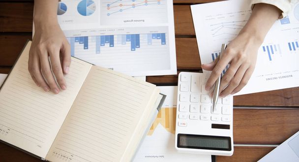 Head of accounting is recording the company's financial growth statistics using graphs as a reference for reviewing and analyzing the results, Taking notes and analyzing data graphs in office. - Photo, Image