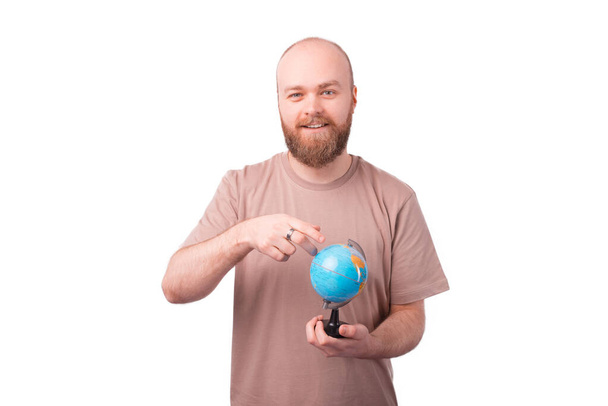 Porträt eines jungen bärtigen Mannes, der auf den Globus zeigt, Reisekonzept - Foto, Bild