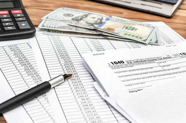 Forma fiscale in busta con documenti finanziari, calcolatrice e denaro su tavolo di legno. - Foto, immagini