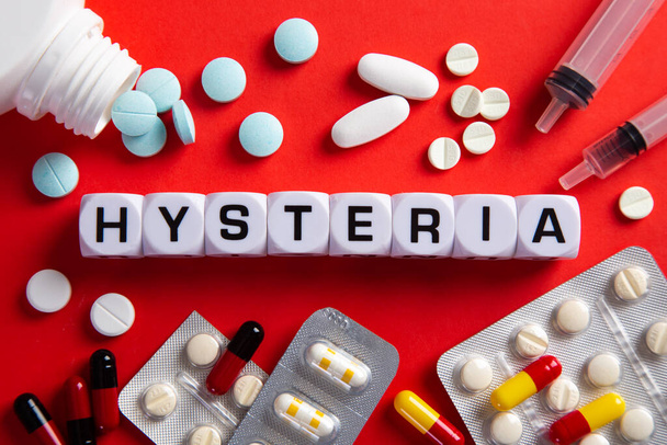 Hysteria medicine word on blocks on red background. Medical concept with pills, vitamins and syringe on the background. - Photo, Image