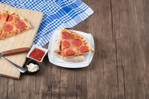 Tranches de pizza Pepperoni dans une assiette en céramique blanche - Photo, image