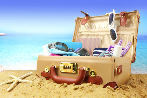 Full open suitcase on tropical beach background  - Photo, Image