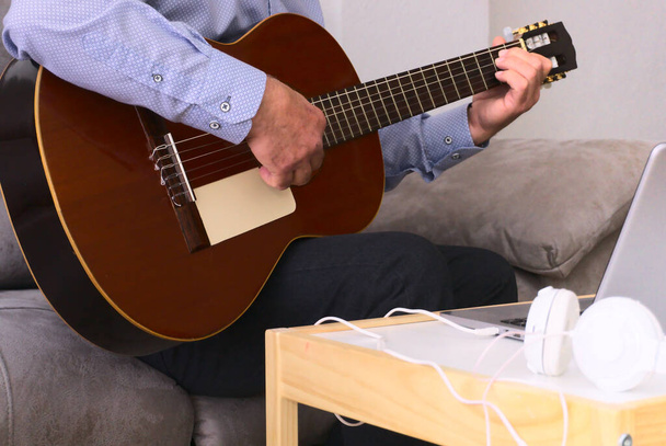 Zbliżenie gitary i ręce 60-latka grającego na gitarze. Muzyka koncepcyjna. - Zdjęcie, obraz
