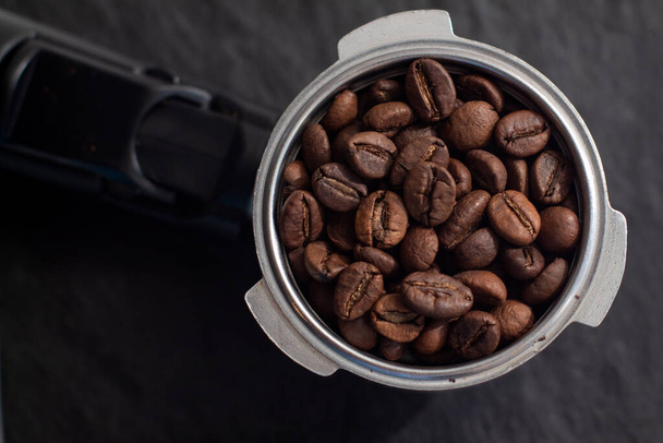 Horn mit Kaffeebohnen. Kaffeemaschine Filterhalter mit Kaffeebohnen auf schwarzer Schiefertafel. - Foto, Bild