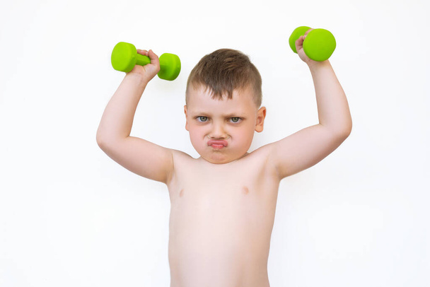 A little boy with green dumbbells smiles on white isolated background - Foto, immagini