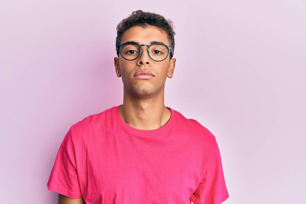 Young handsome african american man wearing glasses over pink background relaxed with serious expression on face. simple and natural looking at the camera.  - Photo, Image