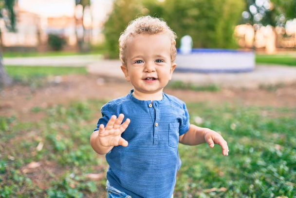 Słodki i szczęśliwy chłopczyk bawiący się w parku w słoneczny dzień. piękne blond włosy mężczyzna maluch zabawy na zewnątrz - Zdjęcie, obraz