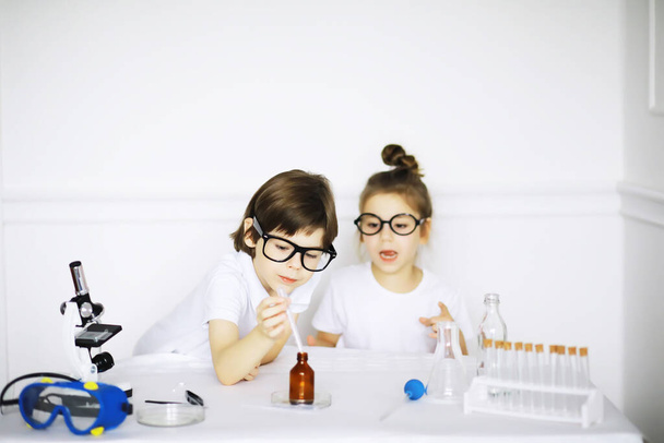 Two cute children at chemistry lesson making experiments isolated on white backgroun - Photo, Image
