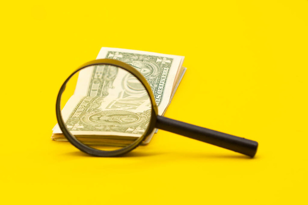 Долларовые купюры и лупа на желтом фоне - Фото, изображение
