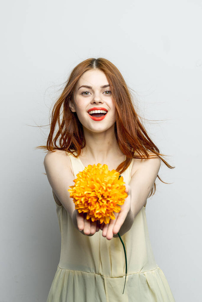 mulher bonita alegre com uma grande flor amarela em suas mãos emoções lábios vermelhos diversão charme - Foto, Imagem