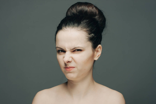 brunette displeased expression holding hand on face gray background - Photo, Image