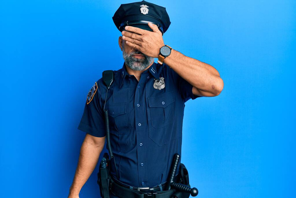 Orta yaşlı, yakışıklı, polis üniforması giyen, gözlerini kapayan, ciddi ve üzgün görünen bir adam. Görme, saklama ve reddetme konsepti  - Fotoğraf, Görsel