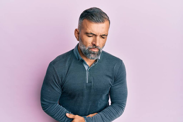 Middle age handsome man wearing casual clothes with hand on stomach because indigestion, painful illness feeling unwell. ache concept.  - Photo, Image