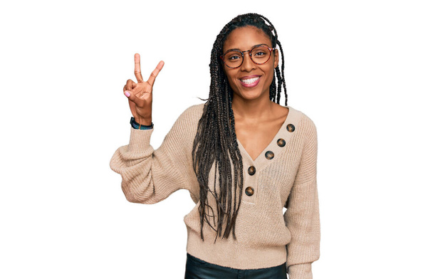 Африканська американка, одягнена в повсякденний одяг, показує і вказує вгору пальцями номер два, посміхаючись упевнено і щасливо.  - Фото, зображення