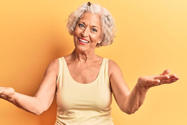 старшая седовласая женщина в повседневной одежде улыбается весело предлагая руки, оказывая помощь и принятие.  - Фото, изображение