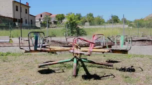 放棄された子供の遊び場で古い空のカルーセルを回す - 映像、動画