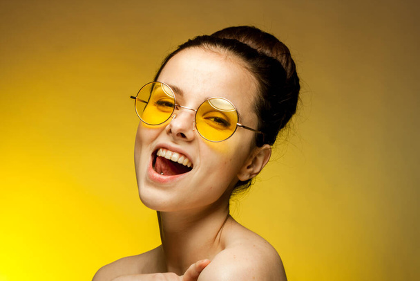 pretty woman naked shoulders yellow glasses emotions charm yellow background - Фото, изображение