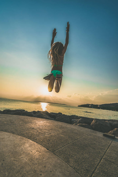 adorable fille en bikini sautant vers le haut au coucher du soleil par la mer - Photo, image