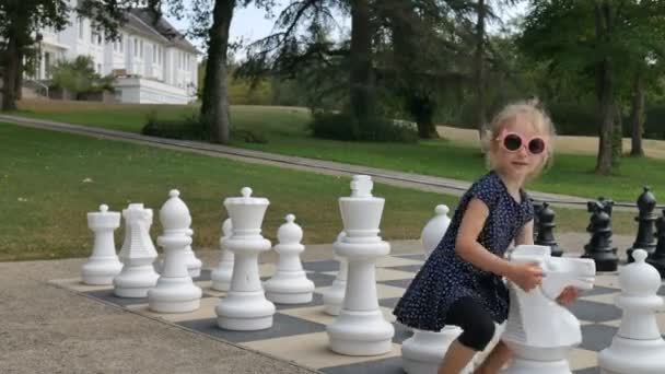 Holčička hraje venku v parku velké šachy. Aktivní dítě, šťastné dětství koncepty - Záběry, video