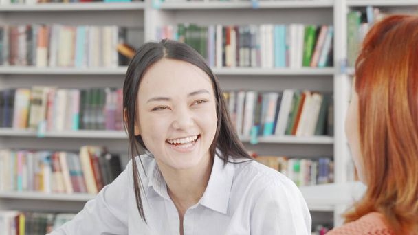 図書館で友人と一緒に勉強を楽しむ魅力的な若いアジアの女性 - 写真・画像