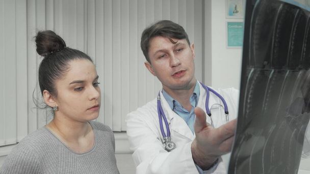 Έμπειρος γιατρός που δείχνει ακτινογραφία σε γυναίκα ασθενή - Φωτογραφία, εικόνα