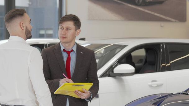 男性の顧客が購入する自動車を選択するのを助ける成熟したセールスマン - 写真・画像