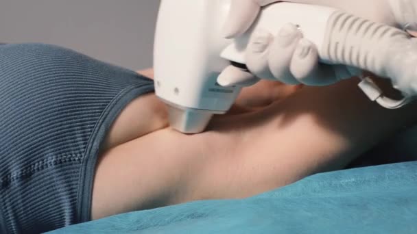 Handen van de schoonheidsspecialiste maken laser epilatie van de oksel gebied aan een jonge vrouw klant in een SPA salon. - Video