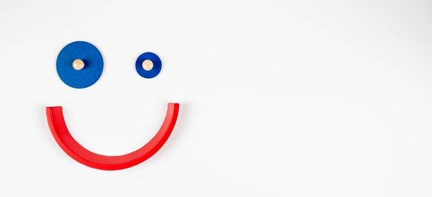 Игрушечное улыбающееся лицо, мультяшный смайлик, минимальный геометрический клоун на белом фоне. Вид сверху - Фото, изображение