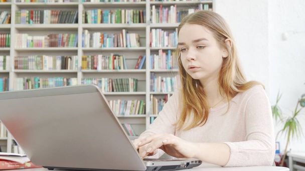 Charming teen girl working on her computer at the library - Photo, Image