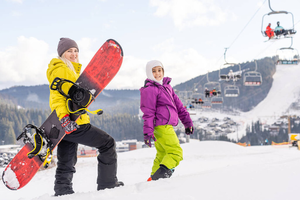 mother and daughter with snowboards in a mountain resort - Photo, Image