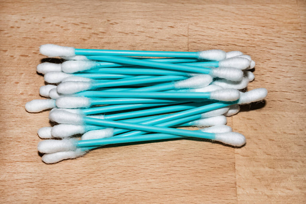 Un bouquet de bâtons d'oreille en plastique turquoise sur fond de bois clair - Photo, image