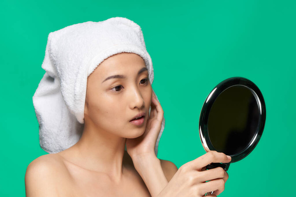 femme d'apparence asiatique regarde dans le miroir avec une serviette sur sa tête peau propre - Photo, image