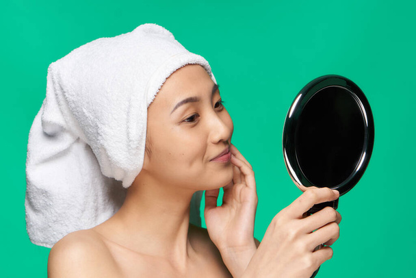 жінка азіатського вигляду дивиться у дзеркало з рушником на її голові чиста шкіра
 - Фото, зображення
