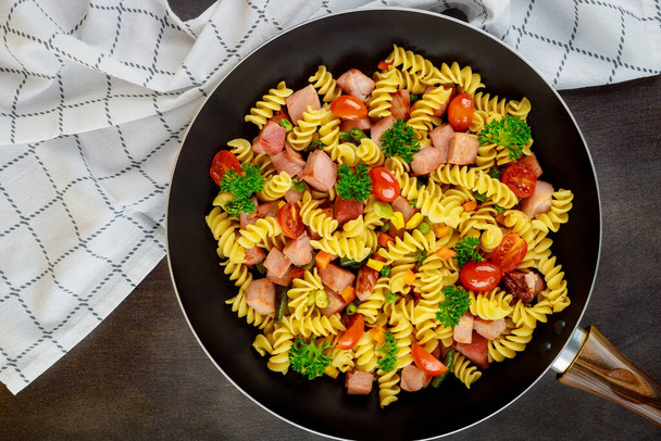 Kleurrijke pasta rotini, kerstomaten en ham op pan. Sluit maar af. Bovenaanzicht. - Foto, afbeelding