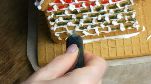 Gingerbread frosting. Chefs female hands decorate with green sugar icing and pastry shop with a bag of gingerbread house in the home kitchen. New year traditions - Footage, Video