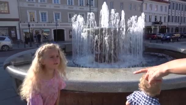 Opgewonden zus en broer kijken naar fontein water stroomt omhoog. Handschot - Video