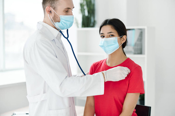 patient examiné par un médecin portant un masque médical, des gants de protection et un stéthoscope - Photo, image