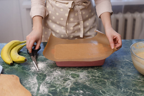 Femme couper du papier de cuisson pour la forme céramique, cuisson. - Photo, image