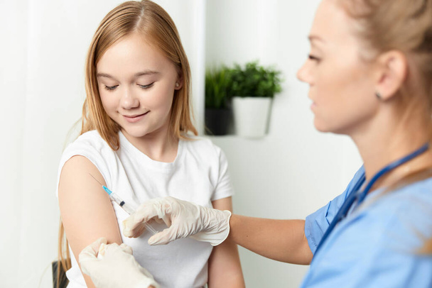 vrouwelijke arts die een meisje een injectie in de armvaccinatie geeft - Foto, afbeelding