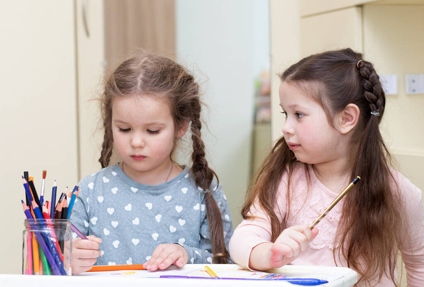 Dos niñas hermosas dibujan con lápices, los niños se dedican a la creatividad, el desarrollo temprano, el aprendizaje de los niños. - Foto, imagen