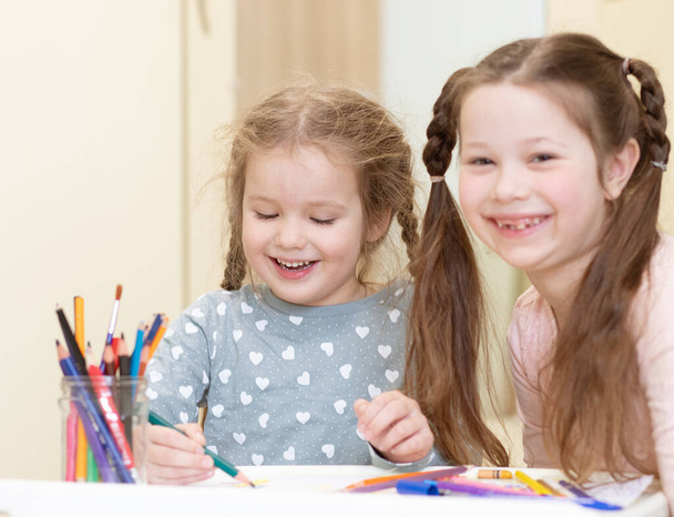 Due belle bambine disegnano con matite, i bambini sono impegnati nella creatività, nello sviluppo precoce, nell'apprendimento dei bambini.. - Foto, immagini