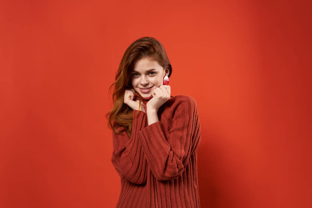 mooie vrouw in rood trui decoratie mode kapsel glamour rode achtergrond - Foto, afbeelding
